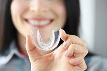 Smiling Woman Holds Transparent Plastic Mouth Guard In Her Hand