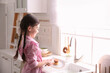 © New Africa - Little girl washing dishes in kitchen at home