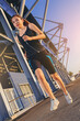 © Panumas - Sporty woman running outdoor beside the stadium. Fit female fitness runner jogging in the city