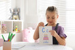 © New Africa - Little girl holding card with letter C and word Cake in classroom at English lesson