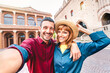Young boyfriend and girlfriend in love having fun taking selfie at old town tour - Wanderlust life style travel concept with tourist couple on city sightseeing vacation
