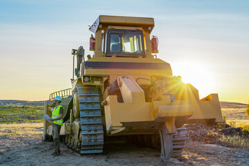 Construction manager, heavy machinery driver next to excavator, bulldozer making roads