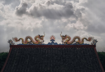 Detail of rooftop of Chinese shrine and temple in Bangkok, Thailand with dramatic sky at sunset