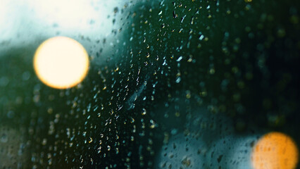 Rain drop on window at night. Condominium or apartment living room window on rainy season night in Bangkok Thailand. Outside window is blurred bokeh of raining city light and natural tree and sky. 