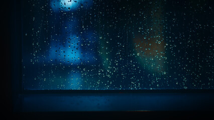 Wall Mural - Rain drop on window at night. Condominium or apartment living room window on rainy season night in Bangkok Thailand. Outside window is blurred bokeh of raining city light and natural tree and sky. 