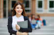© Bangkok Click Studio - Young and beautiful Asian college student girls holding books, pose to camera with group of friends blur in background against school building. Learning and friendship of teens close friend concept