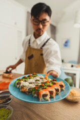 Sushi set on a plate, Chef chef gives a plate to the frame. Food delivery online service. Japanese cuisine: rolls, soy sauce, wasabi. advert for restaurant