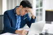 © Bangkok Click Studio - A portrait of a serious businessman sitting at the desk, working on laptop in the modern office, feeling stressed while looking at the computer screen.