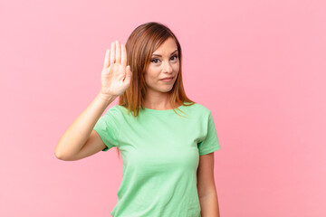 pretty adult woman looking serious showing open palm making stop gesture