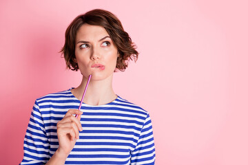 Poster - Portrait of young beautiful thoughtful serious minded girl look copyspace think hold pen on chin isolated on pink color background