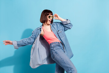 Sticker - Photo of funky charming young woman wear denim shirt dark eyewear dancing smiling isolated blue color background