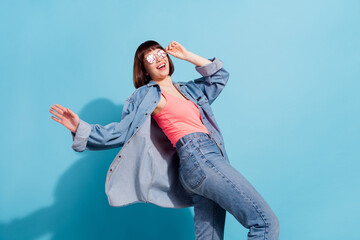 Wall Mural - Portrait of attractive cheerful girl dancing having fun moving touching specs isolated over bright blue color background