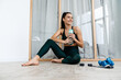 © Drobot Dean - White brunette woman smiling and drinking water while working out