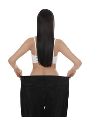 Canvas Print - Young woman wearing big jeans after weight loss on white background, back view