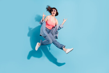 Canvas Print - Full length body size view of attractive cheerful girl jumping showing double horn sign isolated over bright blue color background