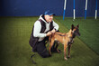 © Svitlana - Instructor seated on the synthetic turf next to a dog
