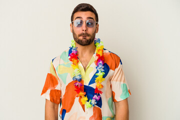 Wall Mural - Young caucasian man dancing on a hawaiian party isolated on white background confused, feels doubtful and unsure.