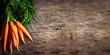 Top view of fresh organic carrot roots on wooden textured kitchen table. Cooking food background banner with copyspace