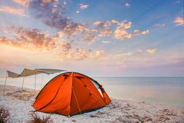 Wall Mural - Camp tent on a beautiful quiet beach near the water against  the sunset sky background