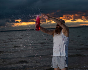 Wall Mural - A humorous portrait of a brutal man pouring soda from a bottle on the beach at sunset