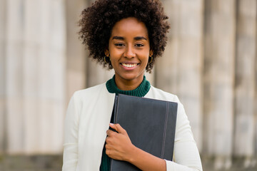 Wall Mural - Afro businesswoman holding clipboard outdoors at the street.