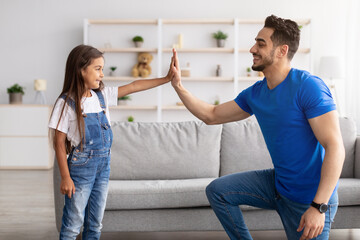 Wall Mural - Father and daughter giving high five in living room