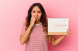 © Asier - Young mexican woman holding a calendar isolated on pink background biting fingernails, nervous and very anxious.