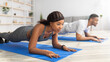 © Prostock-studio - Young black couple standing in elbow plank on yoga mats, doing domestic fitness, exercising their muscles indoors