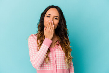 Wall Mural - Young mexican woman isolated on blue background shocked, covering mouth with hands, anxious to discover something new.