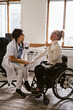 © Maskot - Female doctor examining disabled patient sitting on wheelchair in medical clinic