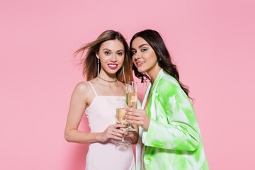 Wall Mural - Pretty women holding glasses of champagne on pink background.