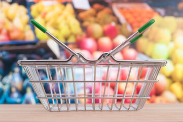 Empty shop basket on blurring supermarket fruit shelf background