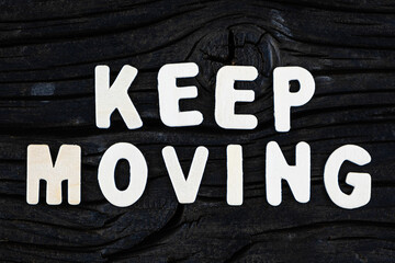 Wall Mural - Keep Moving words on dark wooden background. Business, motivational and inspirational concept.