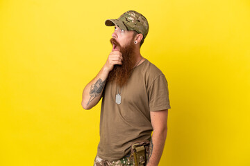 Redhead Military man with dog tag isolated on yellow background having doubts and with confuse face expression