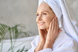 © insta_photos - Happy smiling gorgeous middle aged woman wearing bathrobe and white towel touching face looking at window. Advertising of skin care spa wellness salon procedures concept. Closeup portrait.