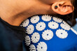 Caucasian female neck on acupressure mat in home self acupuncture massage. Close-up of white woman neck on a blue pillow with thin needles inserted into the body. Alternative medicine.
