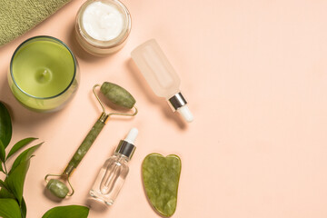 Wall Mural - cosmetic products - jade roller and gua sha massager with cream and serum bottles at pastel backgrou