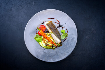 Modern style traditional fried skrei cod fish filet with mashed potato cream and coriander lime relish served as top view on a design plate with copy space