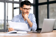 © Kateryna - Successful smart focused young caucasian business man, freelancer or manager sitting at the table in the office, looking through documents, thinking over business strategy, looking at laptop screen