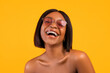Portrait of cheerful black woman in sunglasses laughing, expressing positive emotion on orange studio background