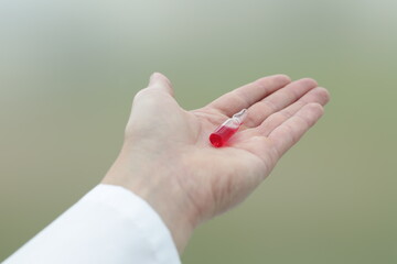 Wall Mural - A glass medical vial of red medicine is in the doctor's hand