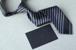 Happy Father’s Day concept idea, cravat or necktie with black gift card on grey background, copy space for text.