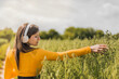girl listening to music outdoors while picking buds from a field. relaxing outdoors. enjoying nature. strolling during a golden sunset. yellow concept.