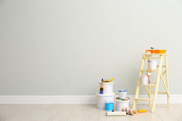 Decorator's kit of tools and paints near light wall indoors. Space for text