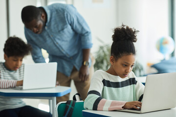 portrait of teenage girl using laptop in school classroom, copy space