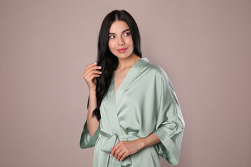 Wall Mural - Pretty young woman in light silk robe on beige background