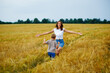 © Elena  - Happy family mother and son in a summer wheat field. The son runs to meet the mother, and she opens her arms for a hug