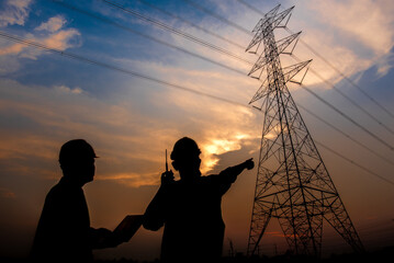 The silhouette of two electrical engineers standing at the power station to see the planning work by producing electricity at high voltage electrodes.