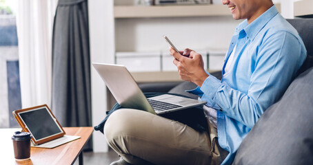 young smiling asian man relaxing using laptop computer working and video conference meeting at home.