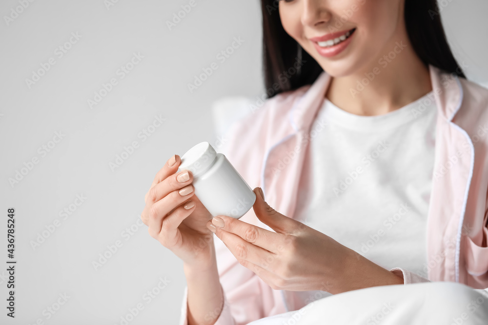 Beautiful young woman taking pills in bedroom